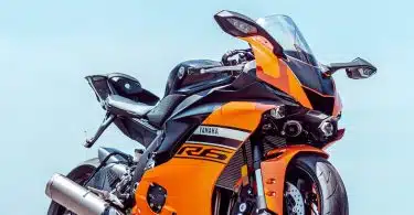 orange and black sports bike parked on gray concrete pavement during daytime