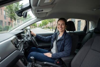 Femme souriante dans sa voiture en ville moderne