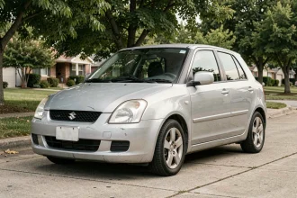 Suzuki Swift 1.3 DDiS d'occasion garée dans une rue résidentielle, vue de trois quarts avant montrant l'état extérieur réaliste d'un modèle usagé