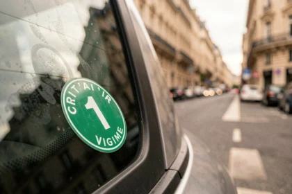 Vignette Crit'Air verte collée sur un pare-brise de voiture dans une rue parisienne